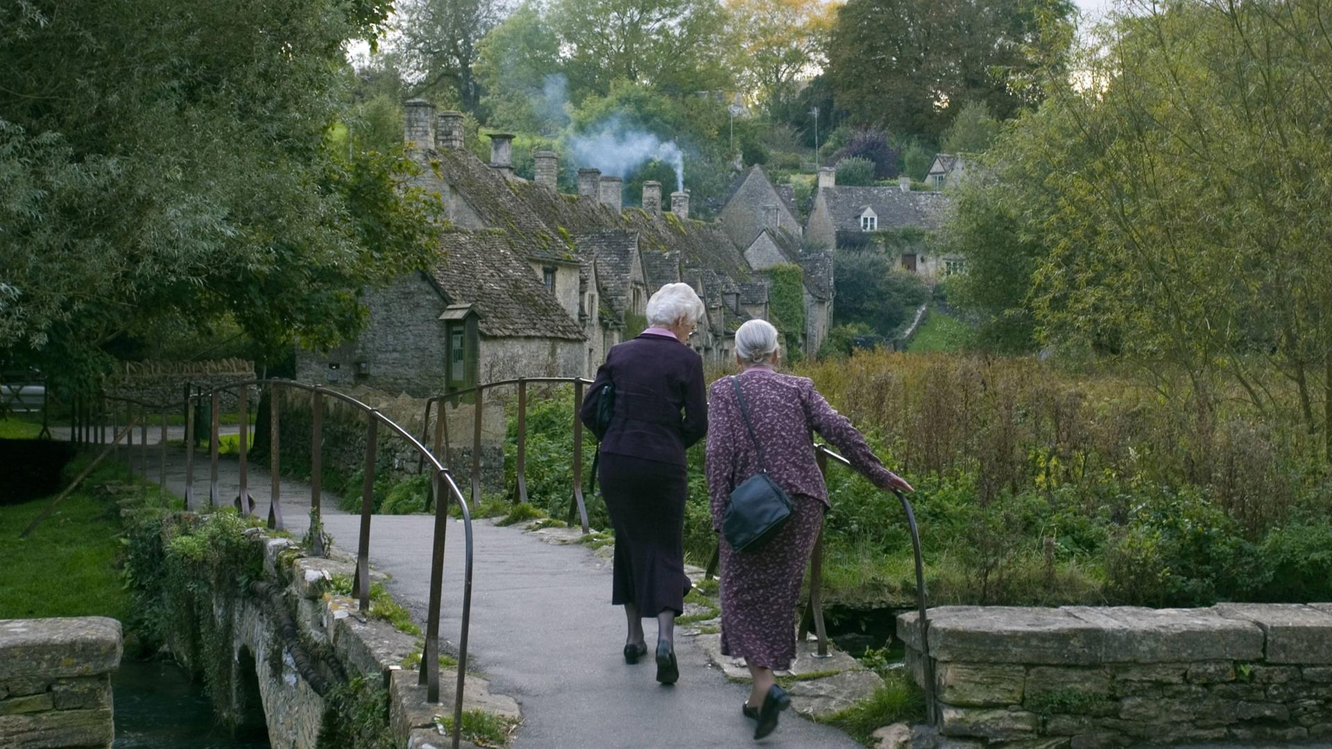 Für die Schwestern wird der Weg von Paris nach Amiens zu einer Reise mit Hindernissen. Zu sehen: Zwei ältere Damen von hinten gehen über eine Brücke.
