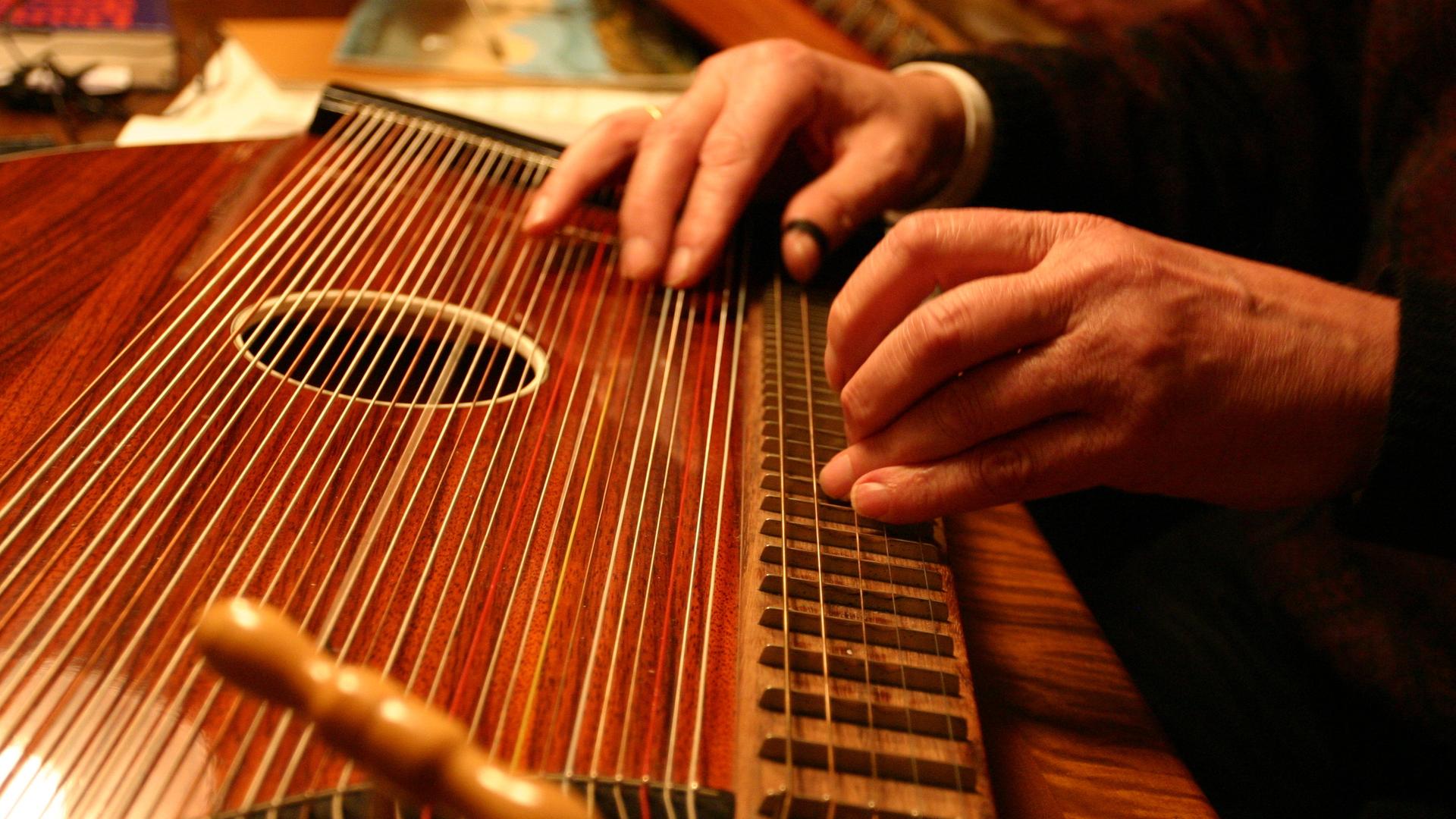 Blick auf zwei Hände, die kundig eine Zither deutscher Bauart spielen. Blick auf zwei Hände, die kundig eine Zither deutscher Bauart spielen.