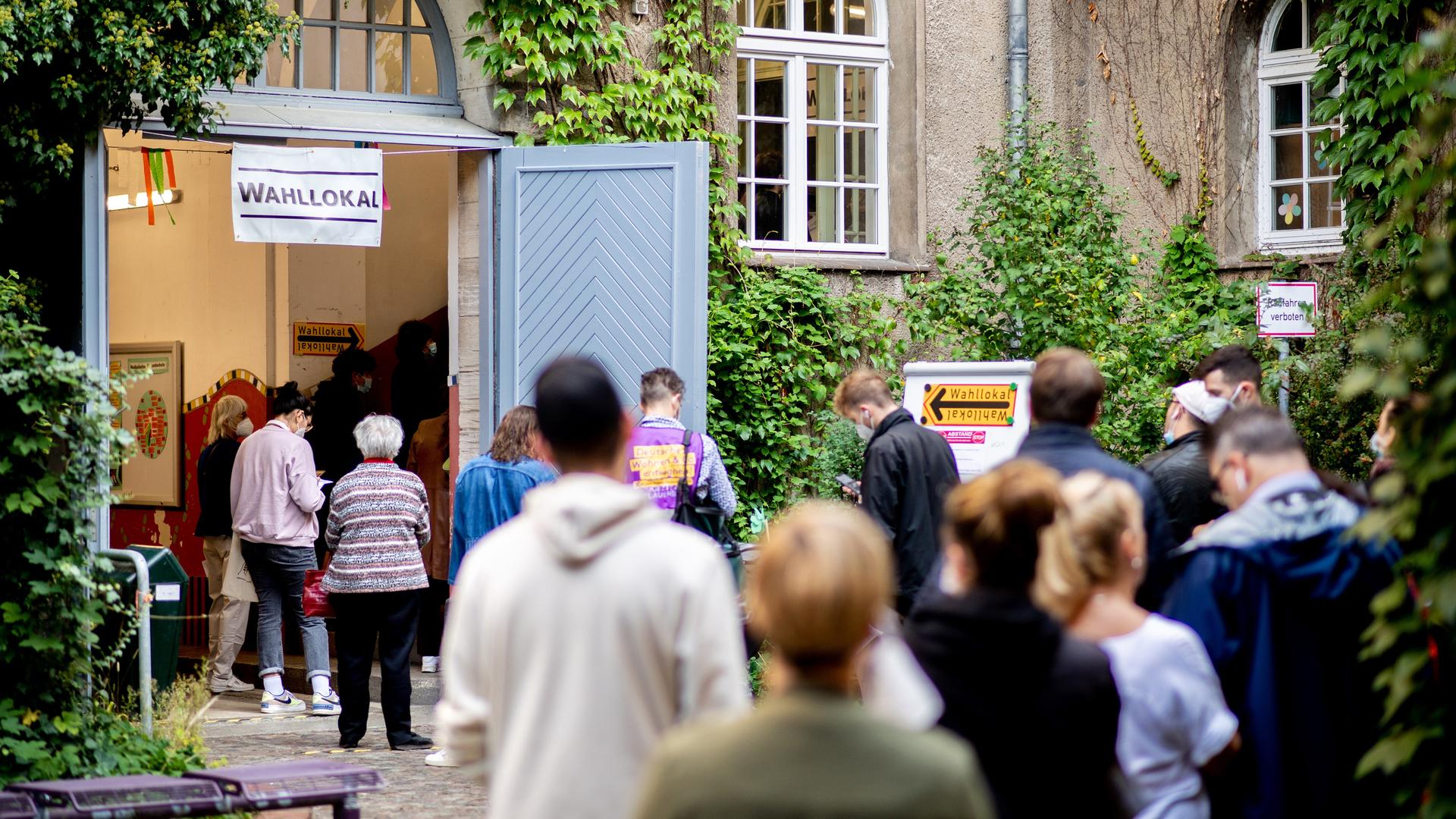 Viele Menschen stehen in Berlin vor einem Wahllokal, das in einer Grundschule untergebracht ist. Viele Menschen stehen in Berlin vor einem Wahllokal, das in einer Grundschule untergebracht ist.
