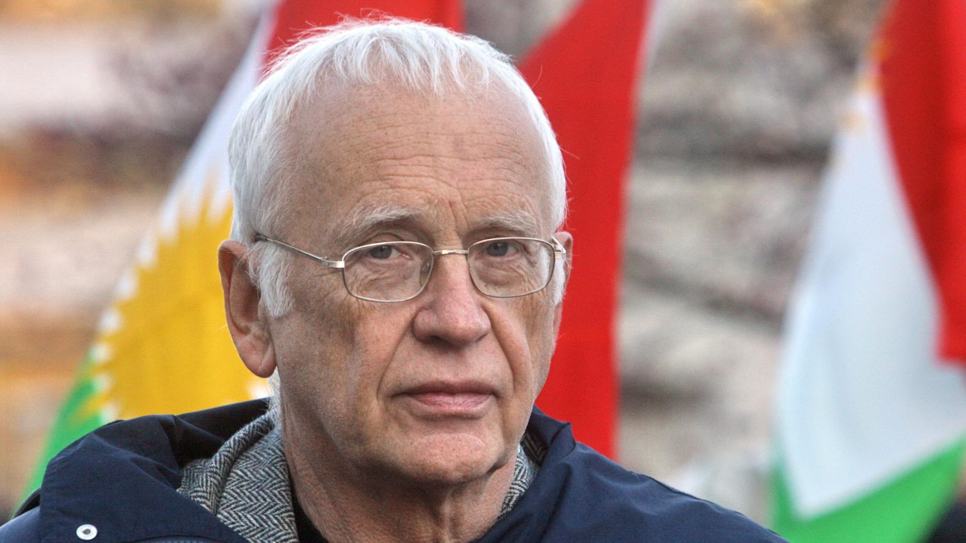 Ein älterer Mann mit weißen Haaren und Brille schaut ernst in die Kamera. Er trägt einen dunkelblauen Mantel. Im Hintergrund sind unscharf bunte Fahnen zu sehen. Das Foto wurde am 10.11.2007 während einer Demonstration in Hamburg aufgenommen. Ein älterer Mann mit weißen Haaren und Brille schaut ernst in die Kamera. Er trägt einen dunkelblauen Mantel. Im Hintergrund sind unscharf bunte Fahnen zu sehen. Das Foto wurde am 10.11.2007 während einer Demonstration in Hamburg aufgenommen.
