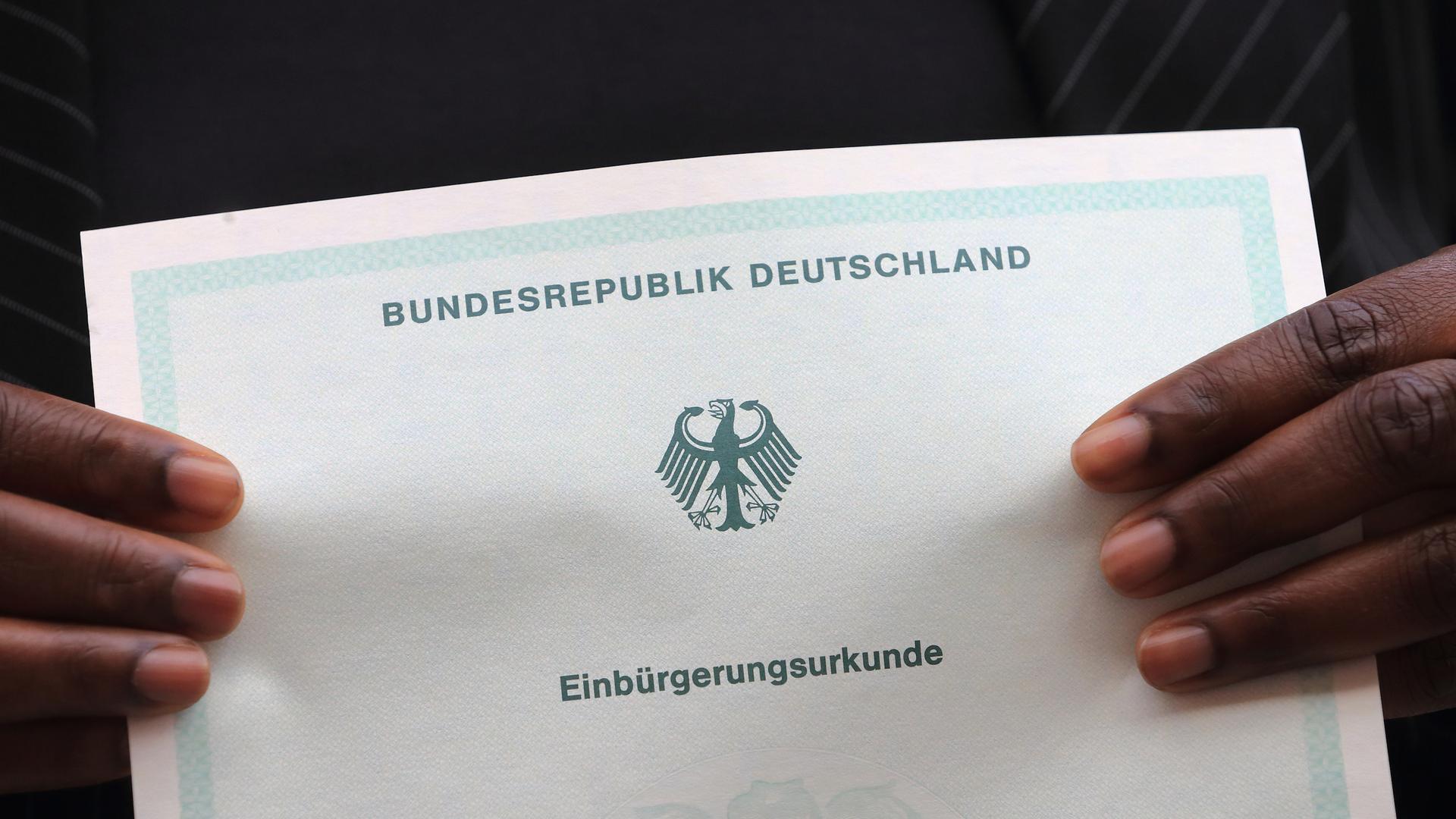 Eine in Afrika geborene Frau hält am 19.10.2013 während des Einbürgerungsfestes in Magdeburg (Sachsen-Anhalt) ihre Einbürgerungsurkunde der Bundesrepublik Deutschland in ihren Händen. Beim ersten landesweiten Einbürgerungsfest wurden zwölf neue deutsche Staatsbürger begrüßt. Eine in Afrika geborene Frau hält am 19.10.2013 während des Einbürgerungsfestes in Magdeburg (Sachsen-Anhalt) ihre Einbürgerungsurkunde der Bundesrepublik Deutschland in ihren Händen. Beim ersten landesweiten Einbürgerungsfest wurden zwölf neue deutsche Staatsbürger begrüßt.