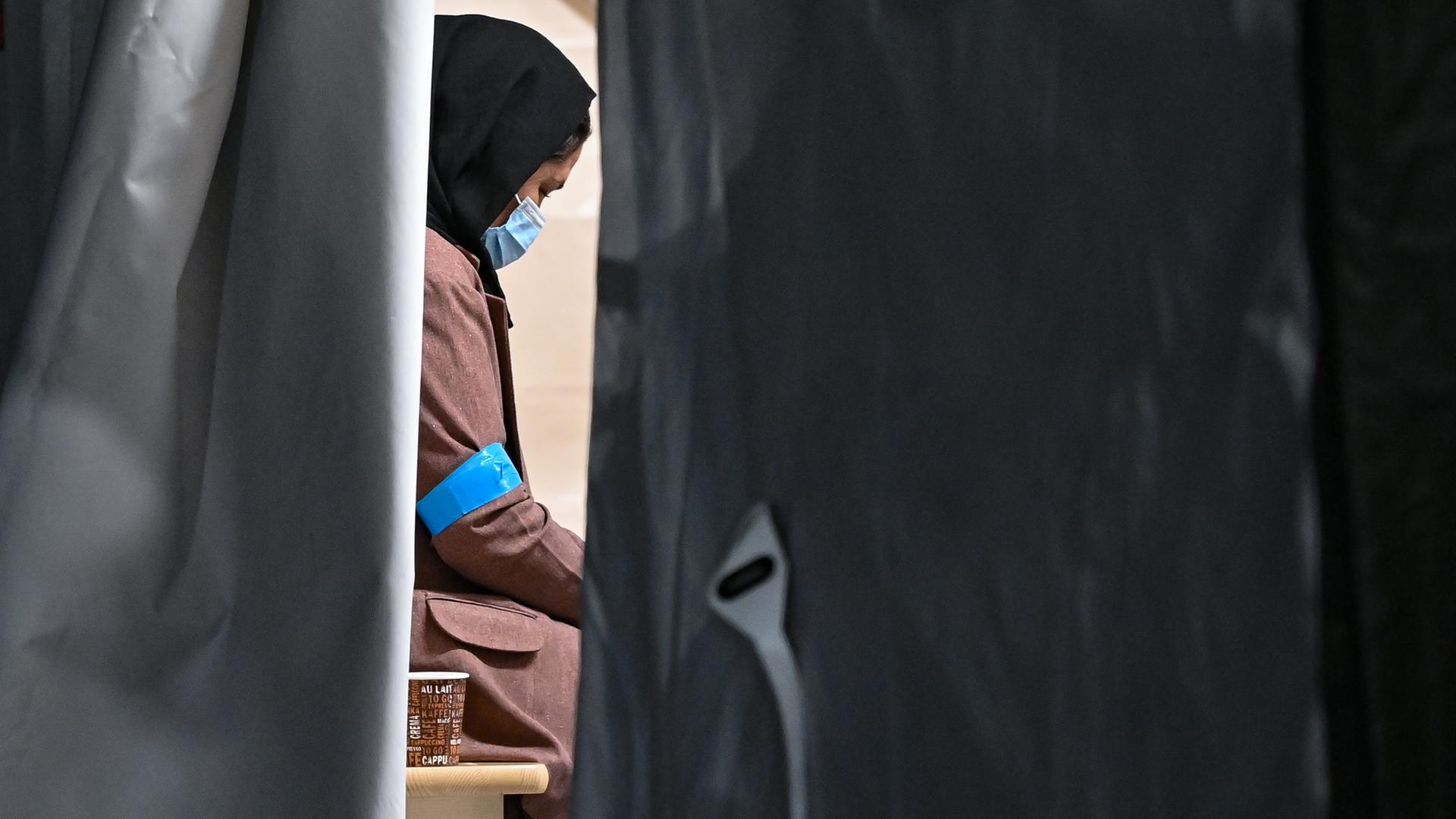 Eine Frau, die zusammen mit weiteren Ortskräften aus Afghanistan auf dem Gelände der DRK-Flüchtlingshilfe in der Erstaufnahmeeinrichtung angekommen ist, sitzt in einem Zelt. Eine Frau, die zusammen mit weiteren Ortskräften aus Afghanistan auf dem Gelände der DRK-Flüchtlingshilfe in der Erstaufnahmeeinrichtung angekommen ist, sitzt in einem Zelt.