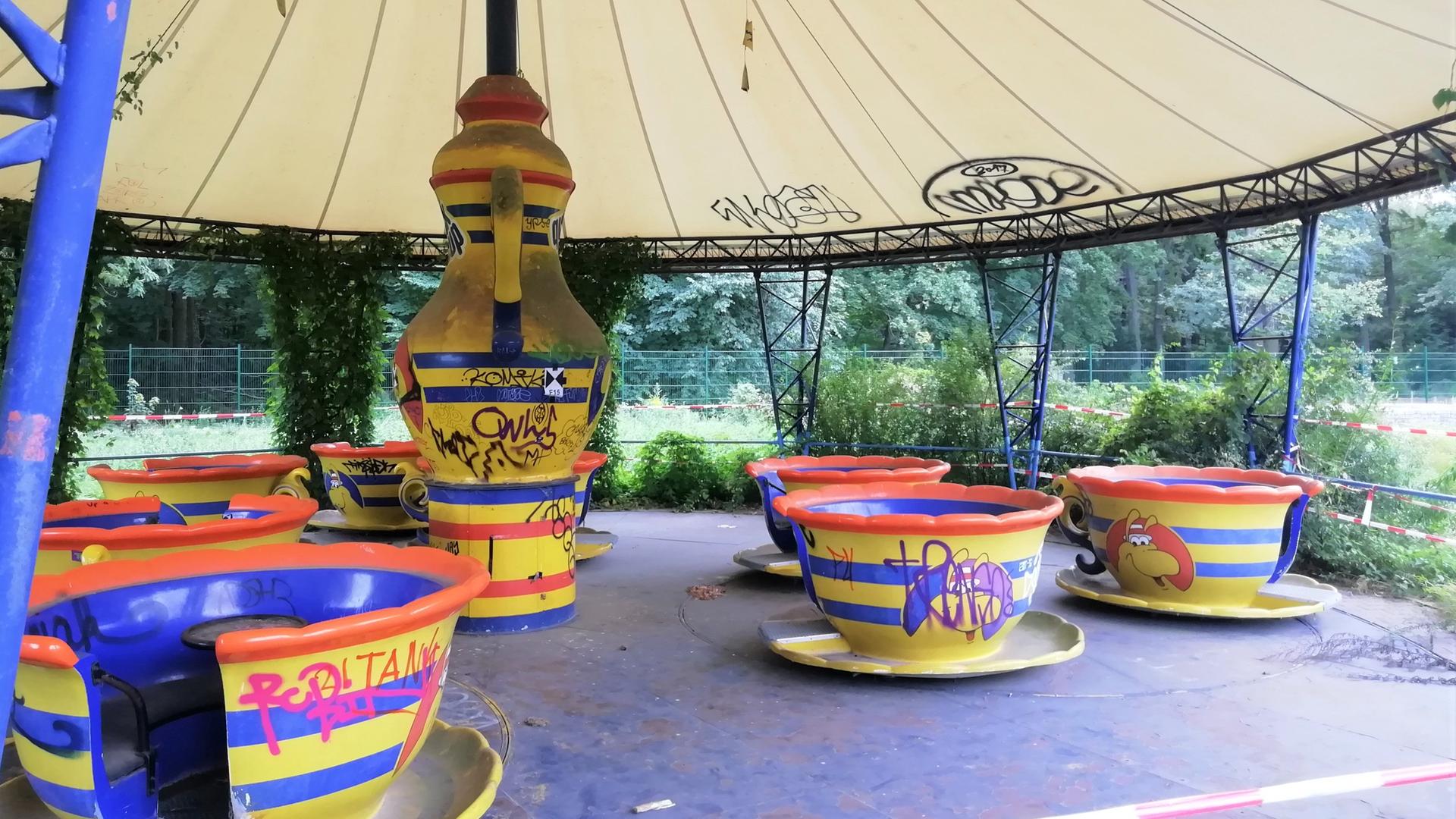 Ein Karussell im Spreepark besteht aus Tassen als Gondeln und einer stilisierten Teekann im Zentrum, um die sich die Tassen drehen. Das Service ist in den Farben Gelb, Rot und Blau gehalten Ein Karussell im Spreepark besteht aus Tassen als Gondeln und einer stilisierten Teekann im Zentrum, um die sich die Tassen drehen. Das Service ist in den Farben Gelb, Rot und Blau gehalten