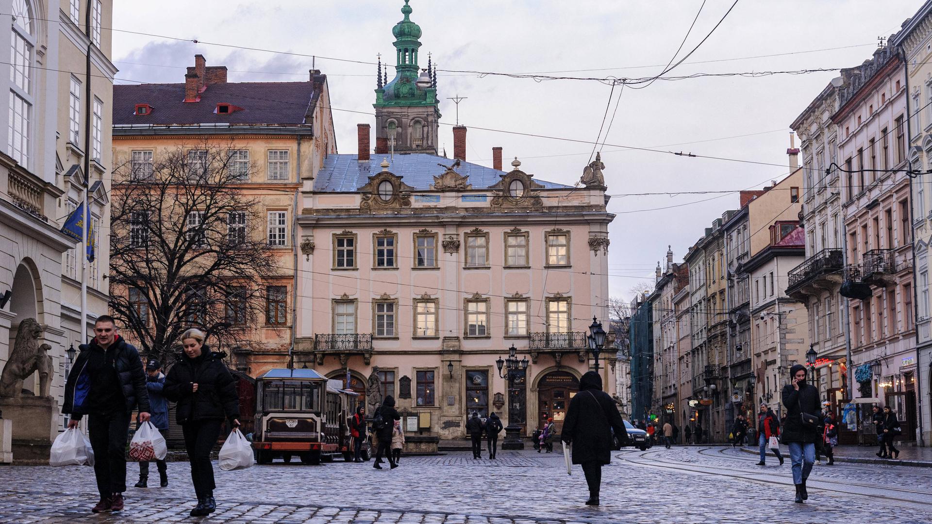 Lwiw in der Westukraine: Menschen laufen über den Marktplatz im Stadtzentrum. Lwiw in der Westukraine: Menschen laufen über den Marktplatz im Stadtzentrum.