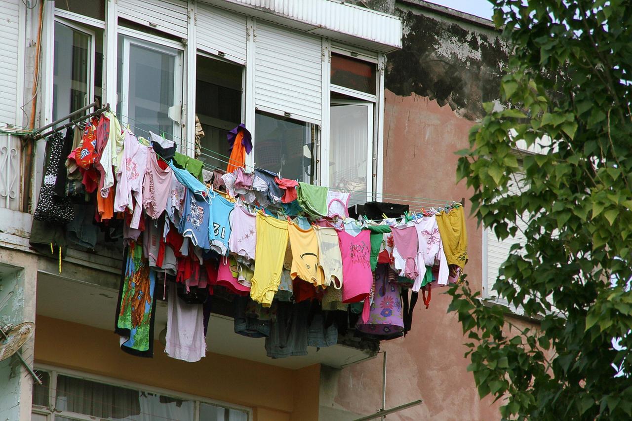 Mehrere Wäscheleinen voll beladen mit bunter Wäsche sind in der Höhe an einem Fenster befestigt. Mehrere Wäscheleinen voll beladen mit bunter Wäsche sind in der Höhe an einem Fenster befestigt.