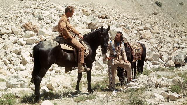 Der US-amerikanische Schauspieler Lex Barker als "Old Shatterhand" auf seinem Pferd zusammen mit Pierre Brice als "Winnetou" und dessen Pferd  in einer Szene der Karl-May-Verfilmung "Winnetou 3". 