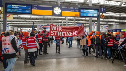 Mit Plakaten und Bannern ziehen Mitglieder der Eisenbahn- und Verkehrsgewerkschaft (EVG) während des bundesweiten Warnstreiks, der gemeinsam mit Verdi stattfindet, durch die Halle des Hauptbahnhof München.