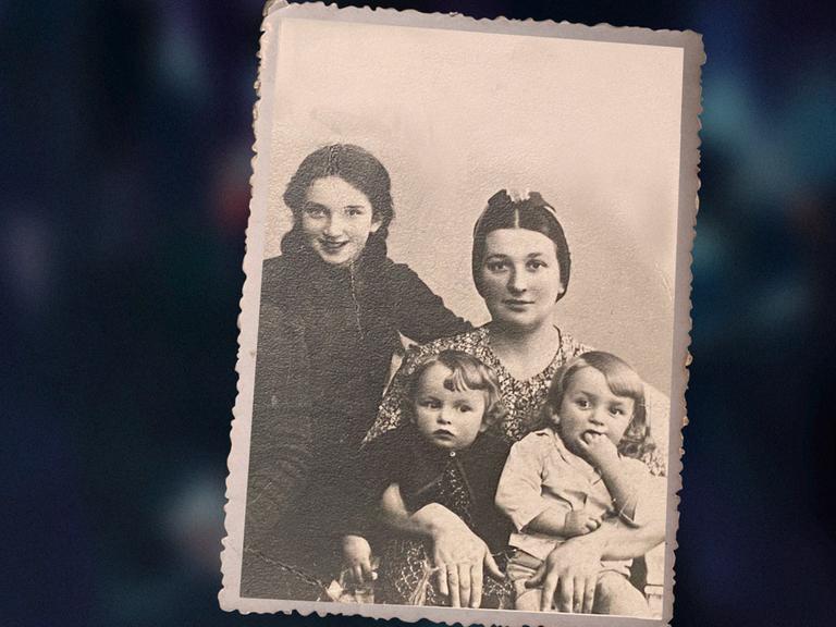 Das Bild zeigt eine alte, schwarzweiße Familienfotografie aus den frühen 1940er . Sie zeigt die dreijährigen Zwillinge Ida und Adam Paluch im Arm ihrer Mutter. Links im Bild ist ihre ältere Schwester Genia zu sehen. 