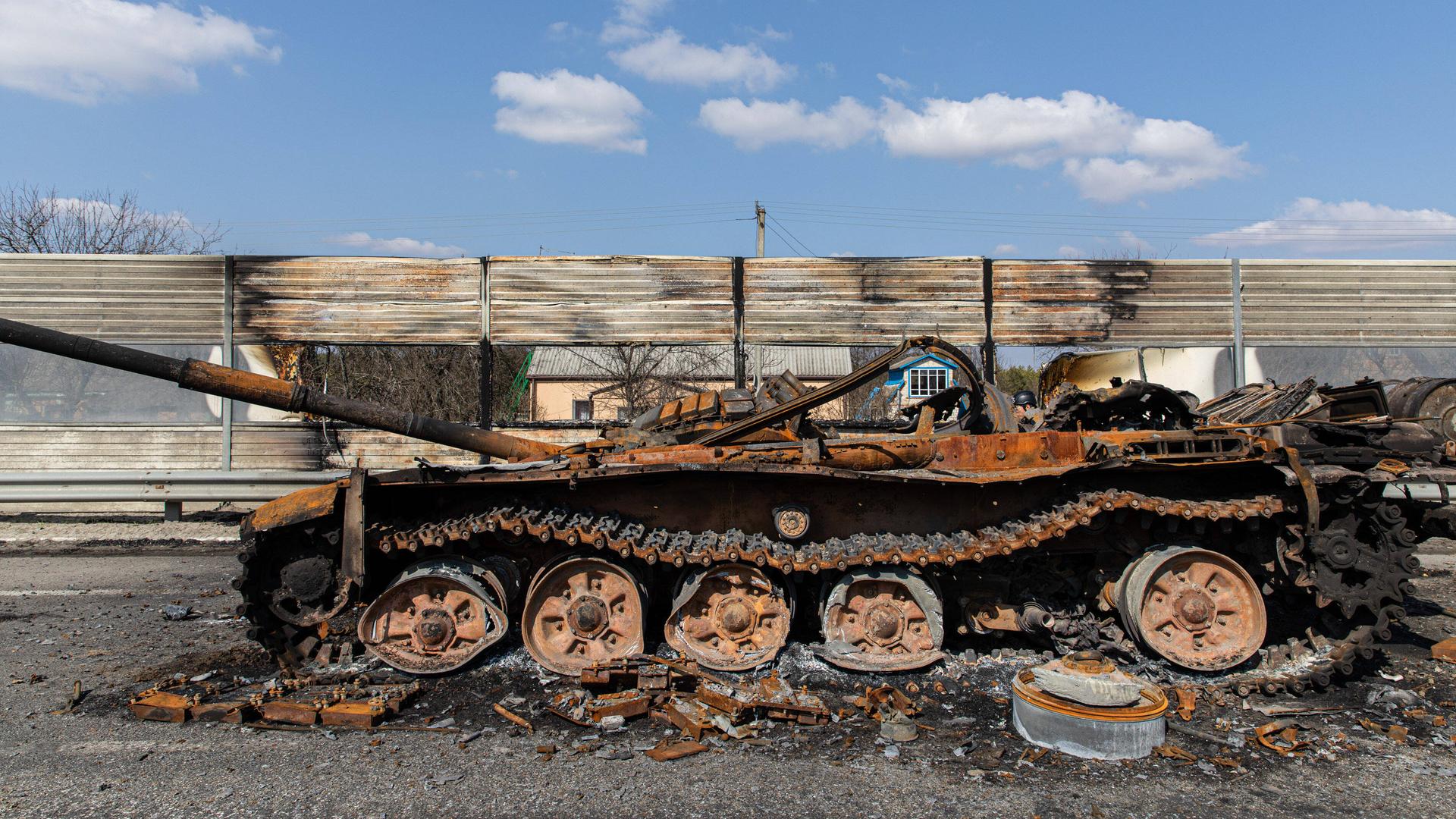 Ein zerstörter, ausgebrannter Panzer auf einer Autobahn Ein zerstörter, ausgebrannter Panzer auf einer Autobahn