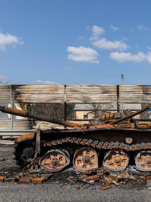 Ein zerstörter, ausgebrannter Panzer auf einer Autobahn