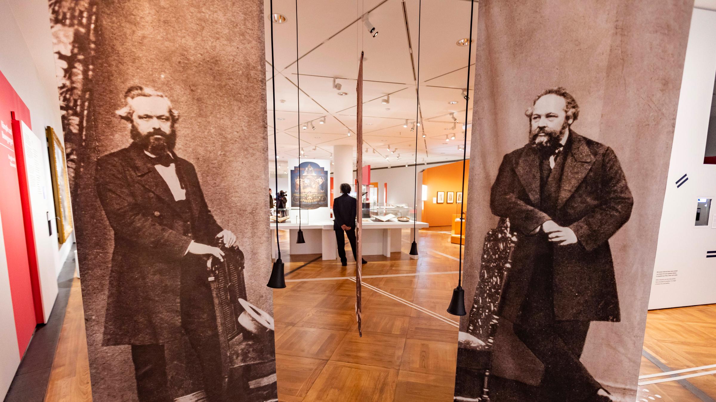 Zwei Poster in einem Ausstellungsraum zeigen zeigen Karl Marx und Micha...</p>

                        <a href=