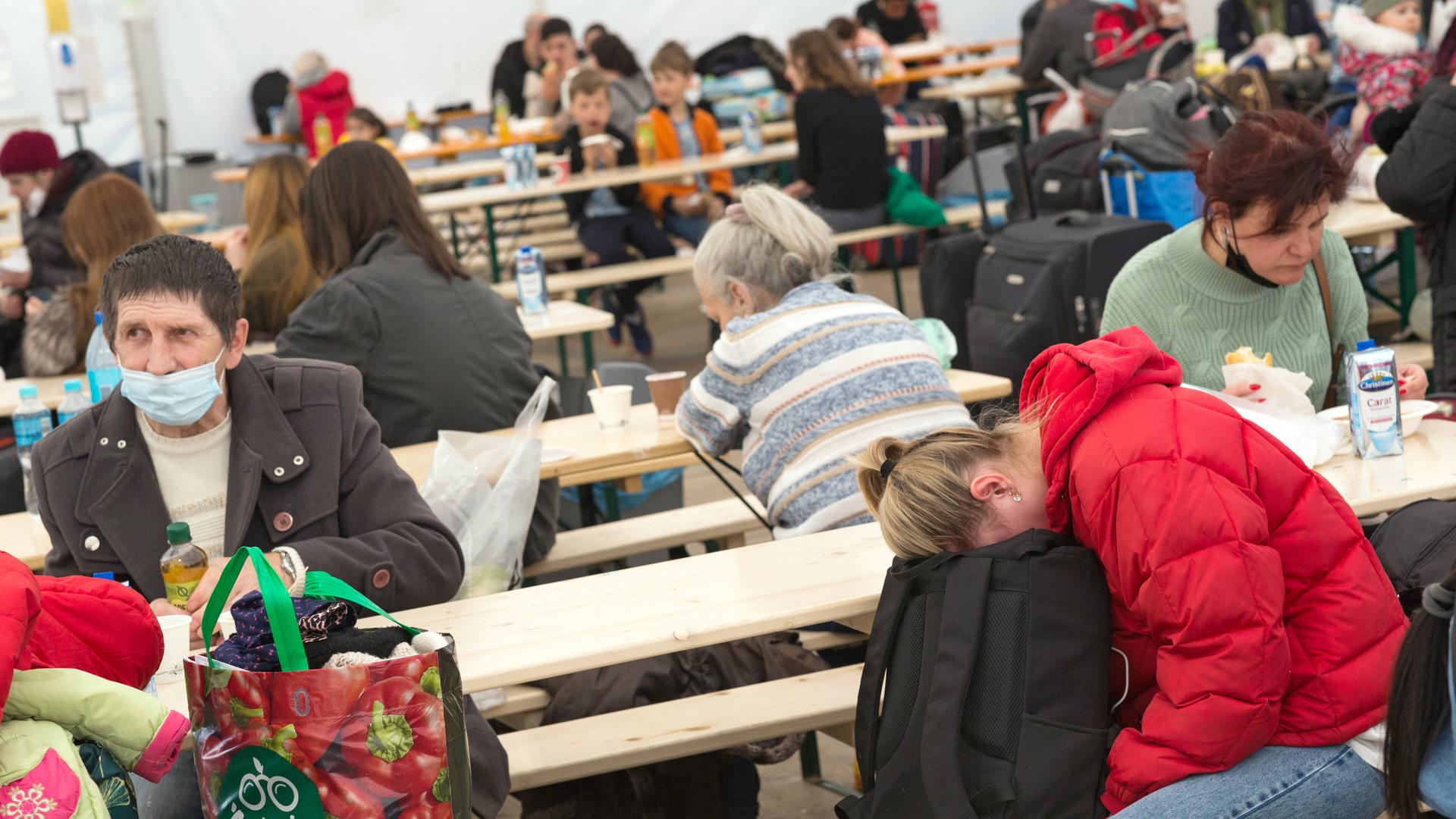 Erschöpfte ukrainische Flüchtlinge sitzen im Willkommenszelt am Berliner Hauptbahnhof auf Holzbänken. Erschöpfte ukrainische Flüchtlinge sitzen im Willkommenszelt am Berliner Hauptbahnhof auf Holzbänken.