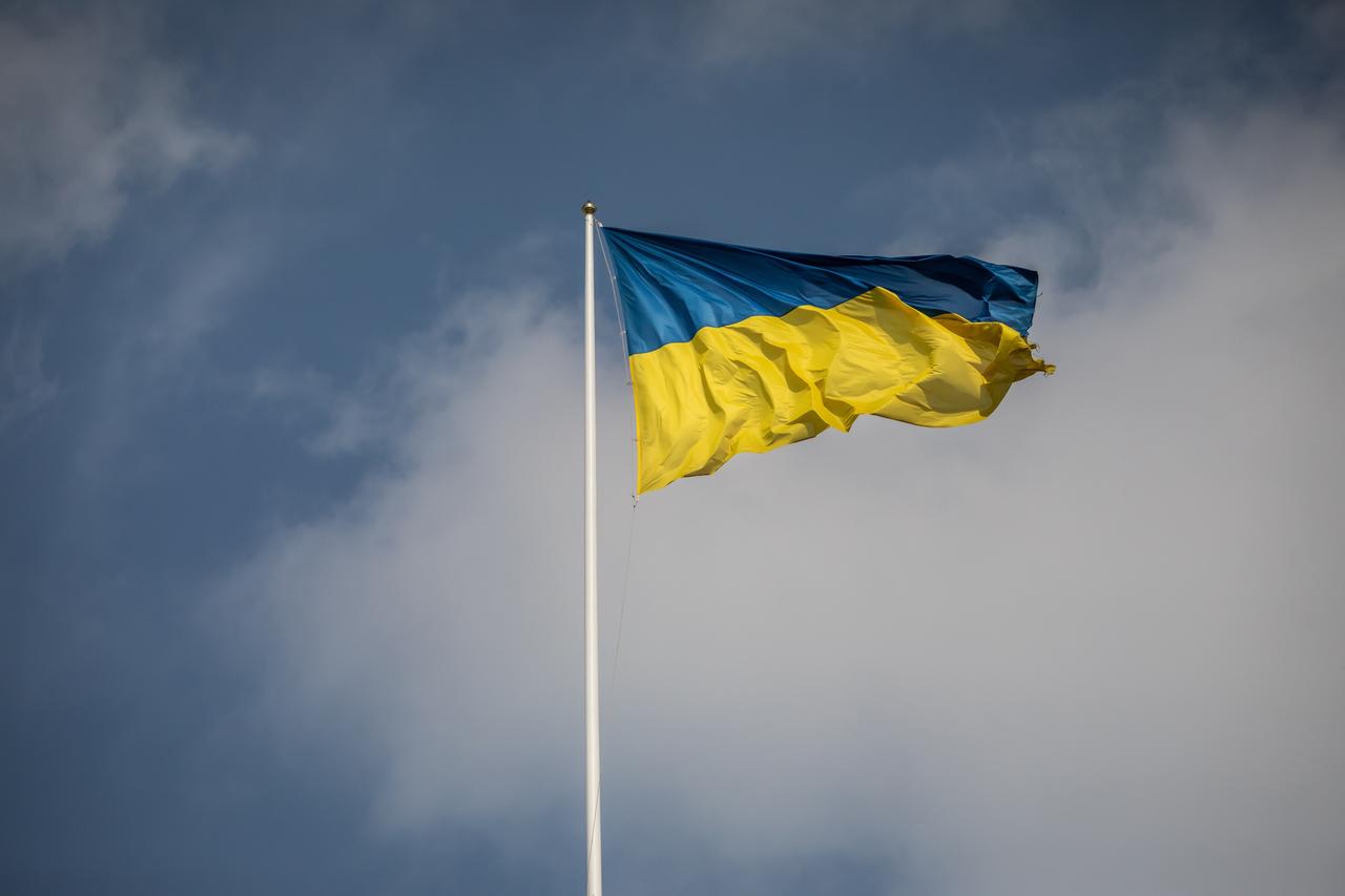 Eine ukrainische Fahne flattert in Kiew im Wind, im Hintergrund blauer Himmel Eine ukrainische Fahne flattert in Kiew im Wind, im Hintergrund blauer Himmel