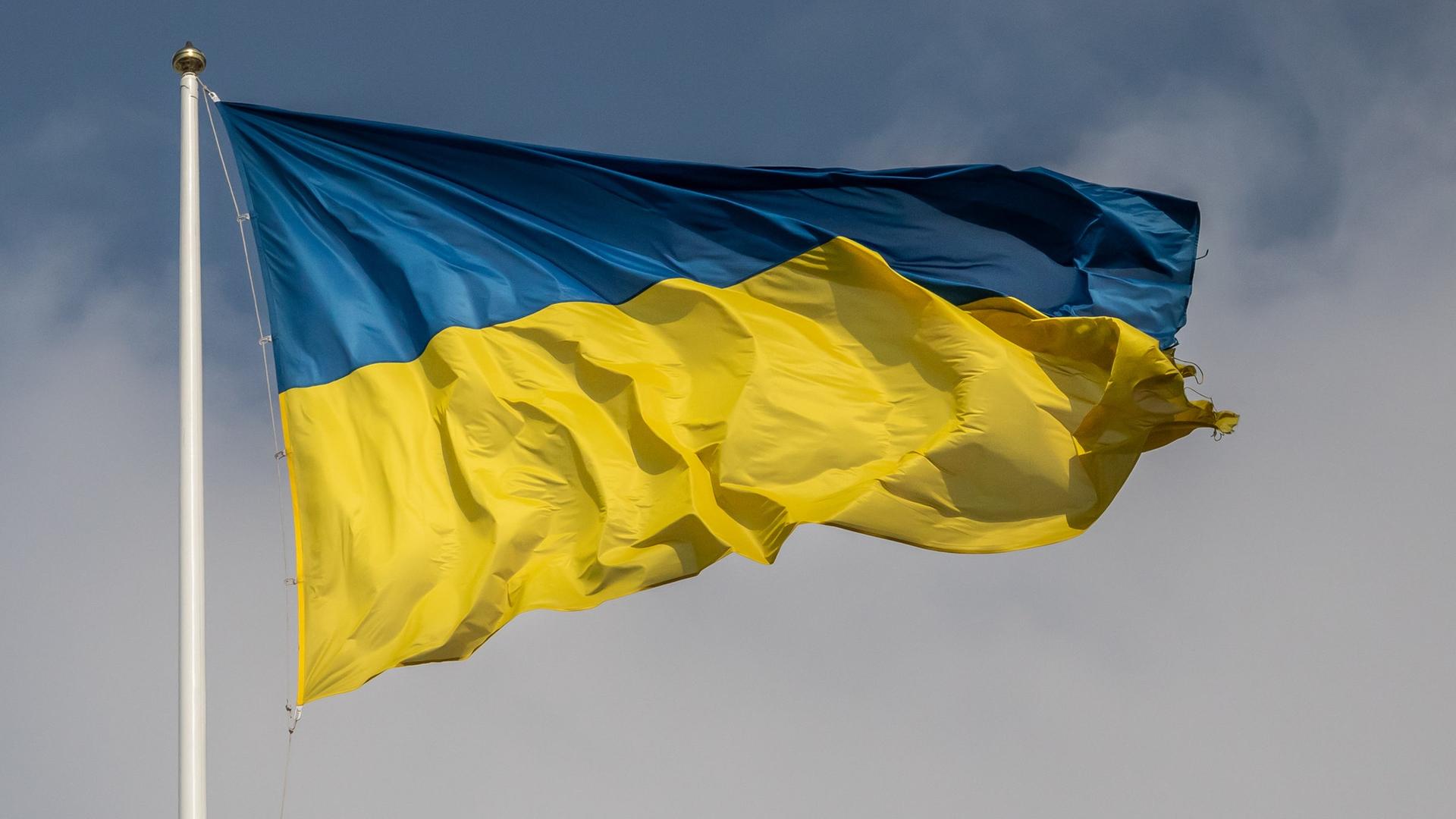 Eine ukrainische Fahne flattert in Kiew im Wind, im Hintergrund blauer Himmel Eine ukrainische Fahne flattert in Kiew im Wind, im Hintergrund blauer Himmel