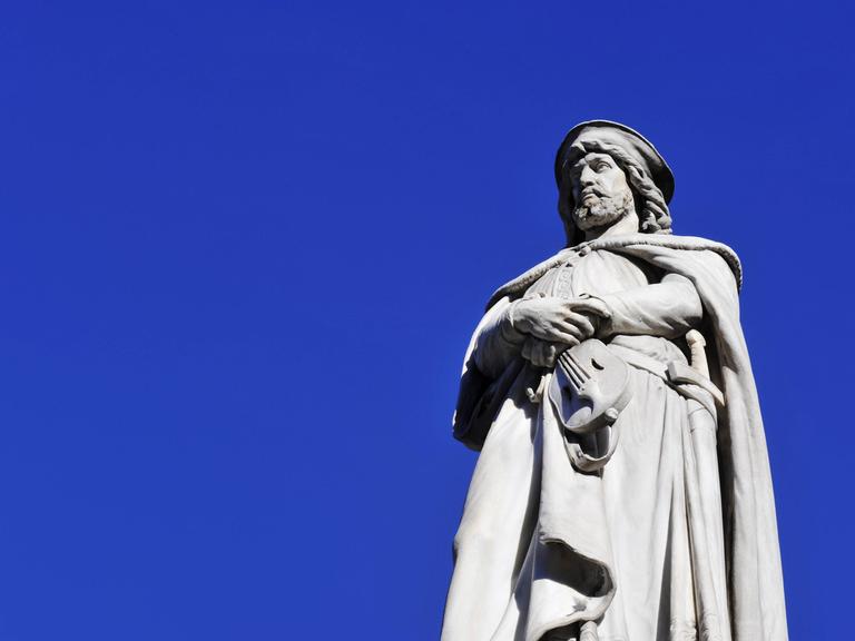 Eine Skulptur von Walther von der Vogelweide ist zum Teil zu sehen. Die Skulptur des deutschsprachigen Mittelalter-Lyrikers ist von unten fotografiert, der Hintergrund ist blau.