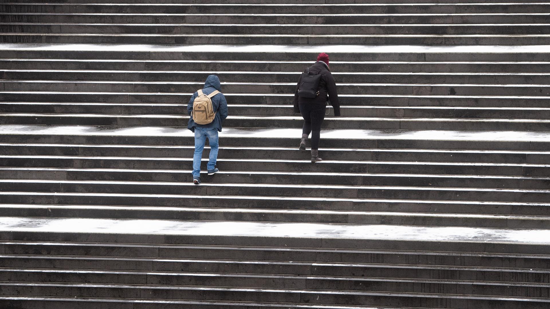 Passanten gehen über eine leicht verschneite Treppe am Raschplatz in der Innenstadt von Hannover.
