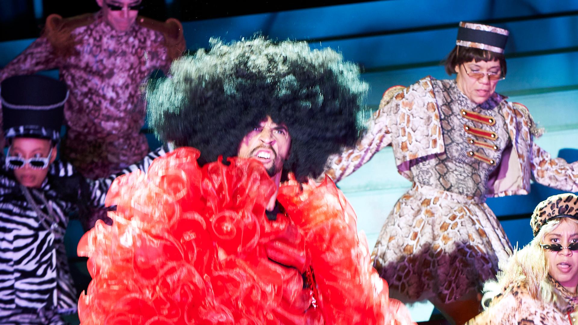 Schauspieler tragen auf einer Theaterbühne Kostüme, die an Karneval erinnern. Schauspieler tragen auf einer Theaterbühne Kostüme, die an Karneval erinnern.