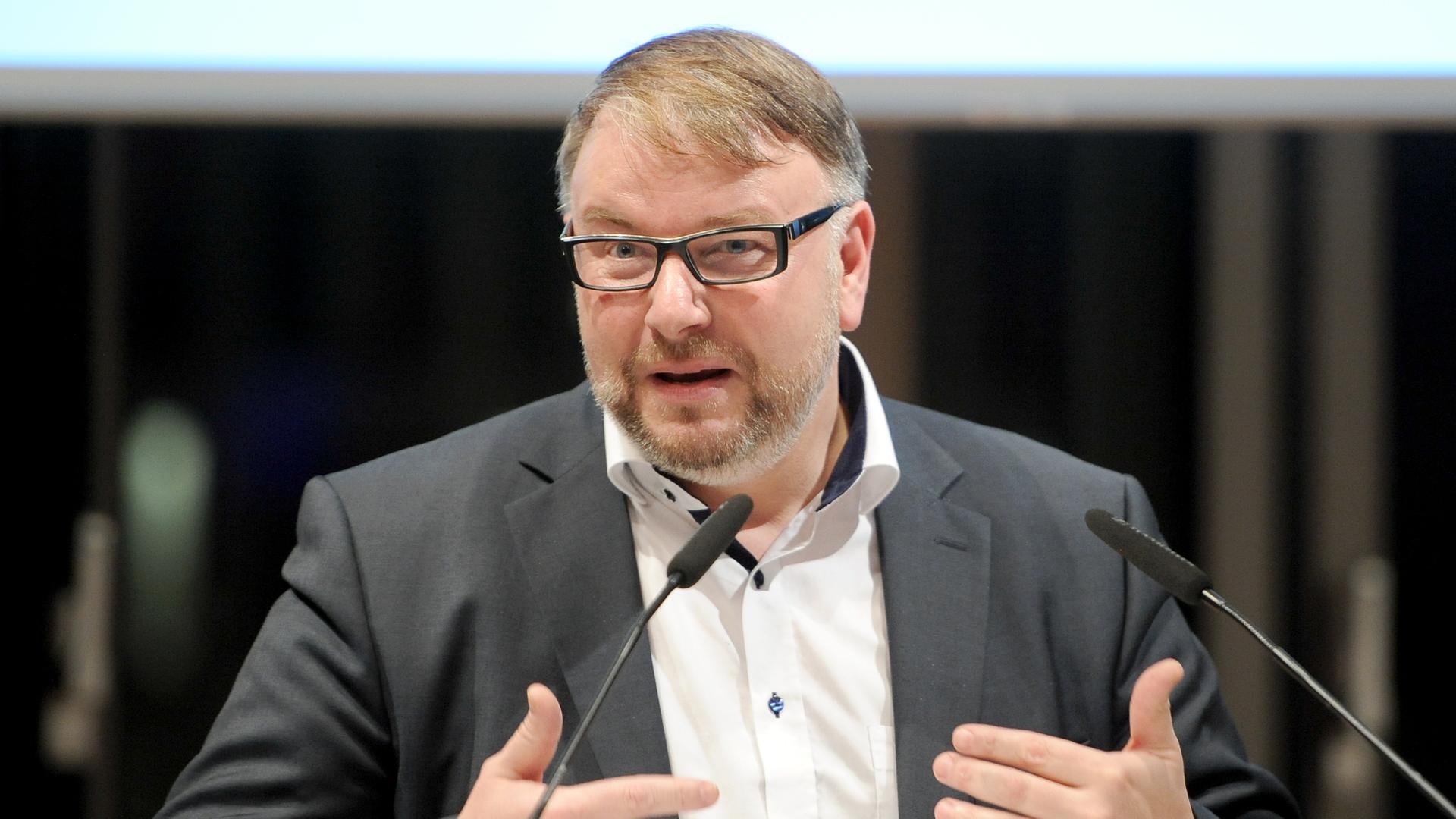 Der Geschäftsführer des Fonds Darstellende Künste, Holger Bergmann, spricht an zwei Mikrofonen Der Geschäftsführer des Fonds Darstellende Künste, Holger Bergmann, spricht an zwei Mikrofonen