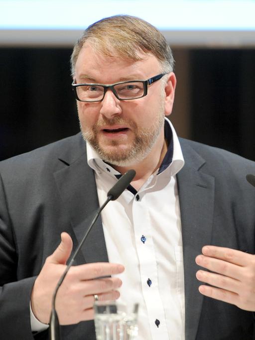 Der Geschäftsführer des Fonds Darstellende Künste, Holger Bergmann, spricht an zwei Mikrofonen