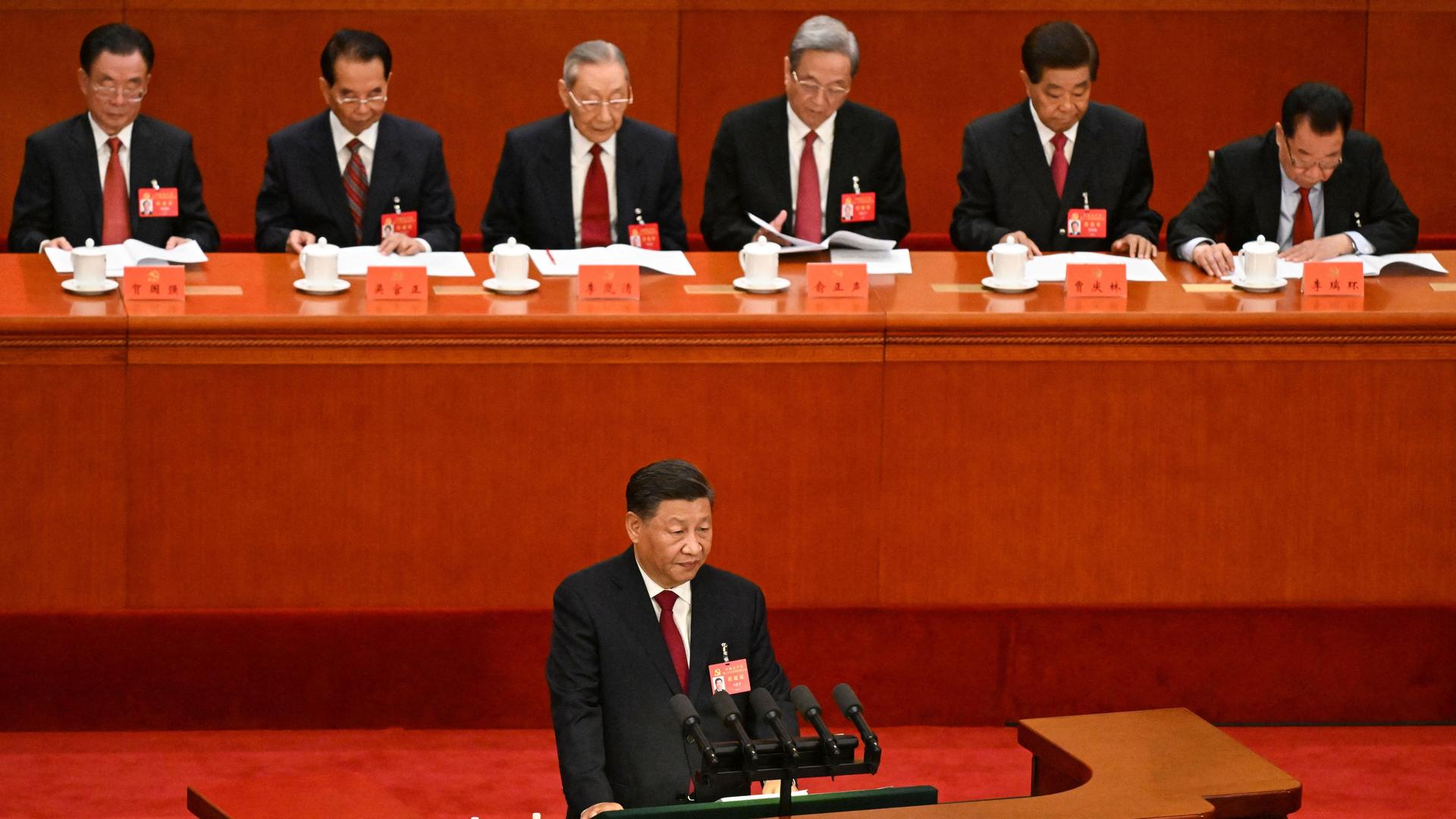 Chinas Staats- und Regierungschef Xi steht an einem Rednerpult, hinter ihm Delegierte des Parteitags in der Großen Halle des Volkes