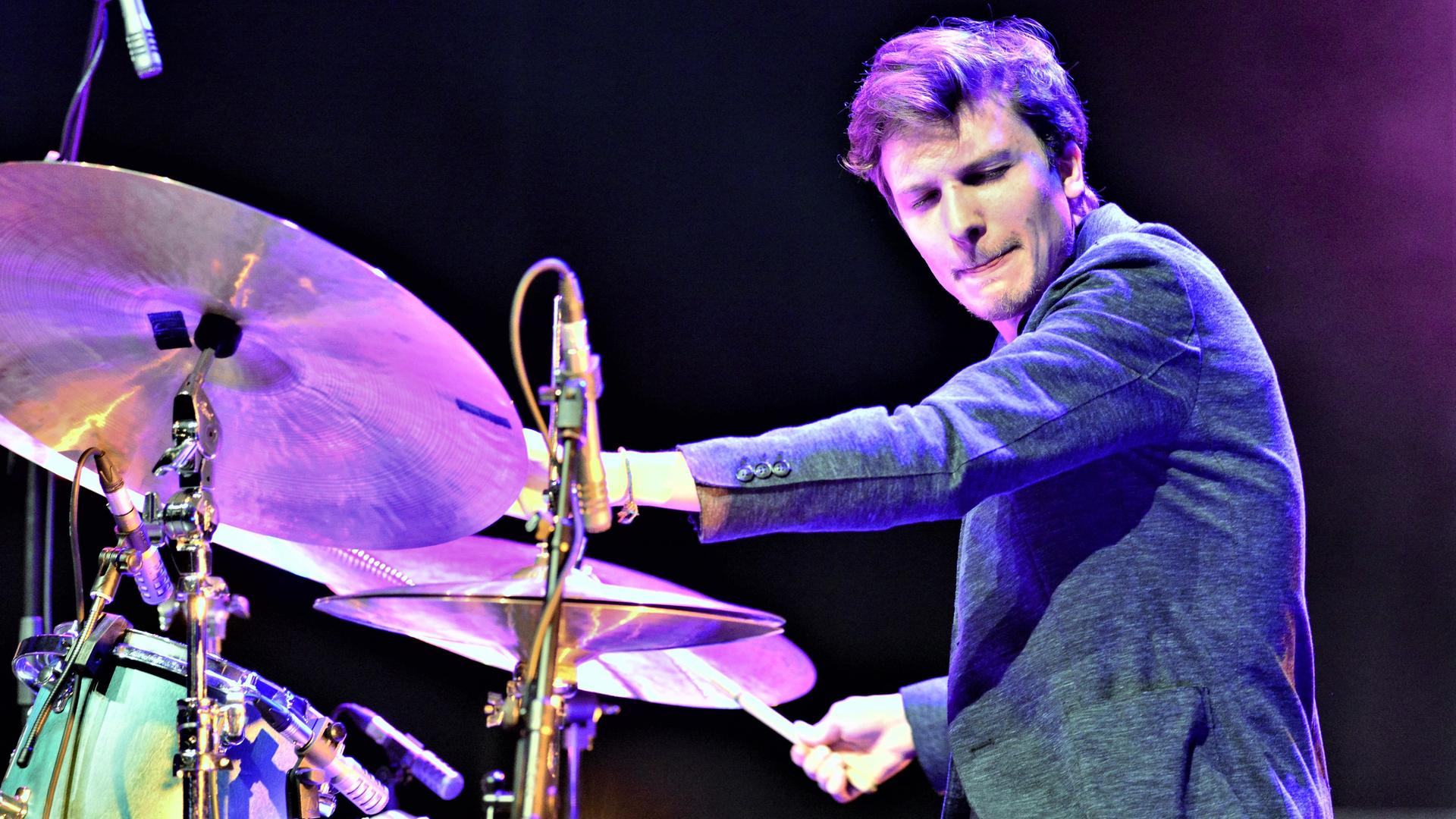 Ein Schlagzeuger spielt auf seinem Instrument und schaut mit geschlossenen Augen konzentriert zur Seite.
