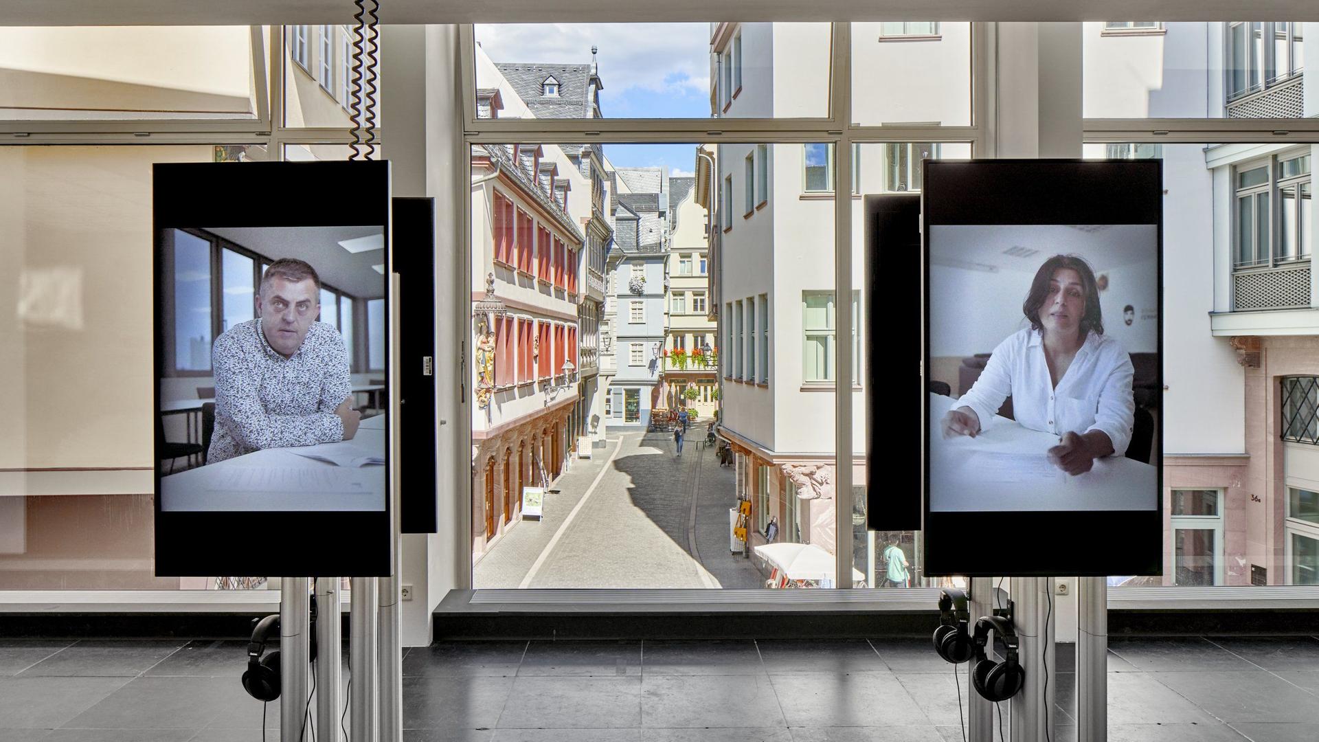 In der Frankfurter Ausstellung äußern sich Angehörige und Überlebende auf zwei Bildschirmen in Videos zum Attentat in Hanau. In der Frankfurter Ausstellung äußern sich Angehörige und Überlebende auf zwei Bildschirmen in Videos zum Attentat in Hanau.