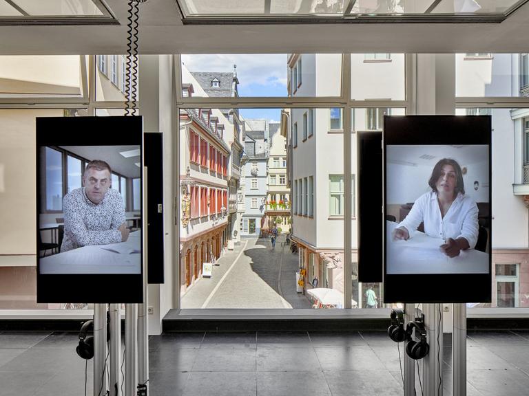 In der Frankfurter Ausstellung äußern sich Angehörige und Überlebende auf zwei Bildschirmen in Videos zum Attentat in Hanau.