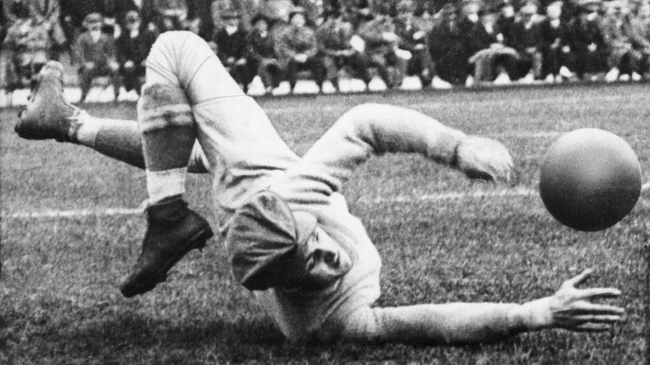 Schwarzweißfoto von einem historischen Fußballspiel. Ein Torhüter liegt auf dem Fußballfeld und fängt einen Fußball. Schwarzweißfoto von einem historischen Fußballspiel. Ein Torhüter liegt auf dem Fußballfeld und fängt einen Fußball.