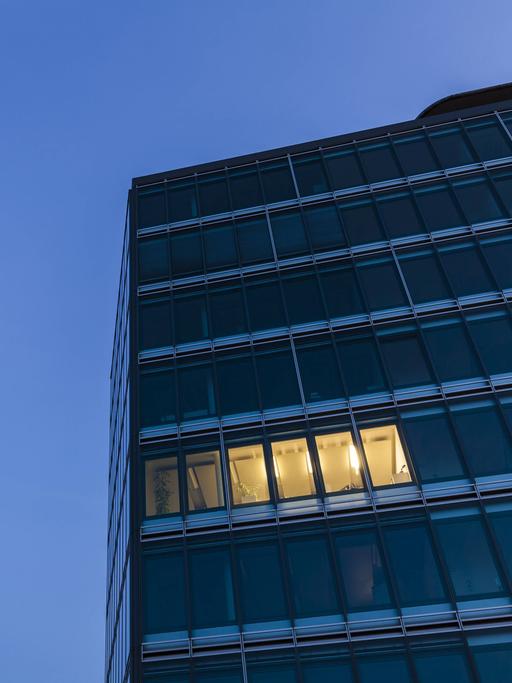 Nächtliches Bürogebäude mit einigen hellen Fenstern.