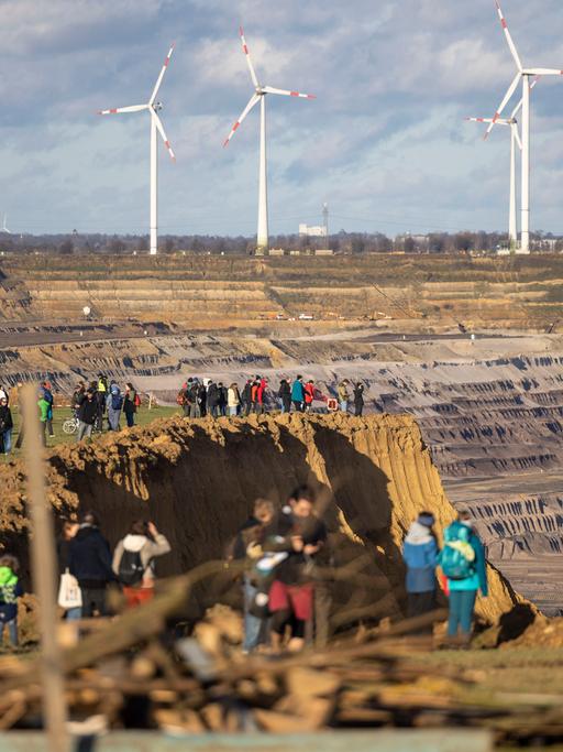 Besucher stehen direkt an der Kante des Tagebaus Garzweiler II in Lützerath, derweil bauen Aktivisten weitere Barrikaden. Lützerath soll zur Erweiterung des Braunkohletagebaus Garzweiler II abgebaggert werden.