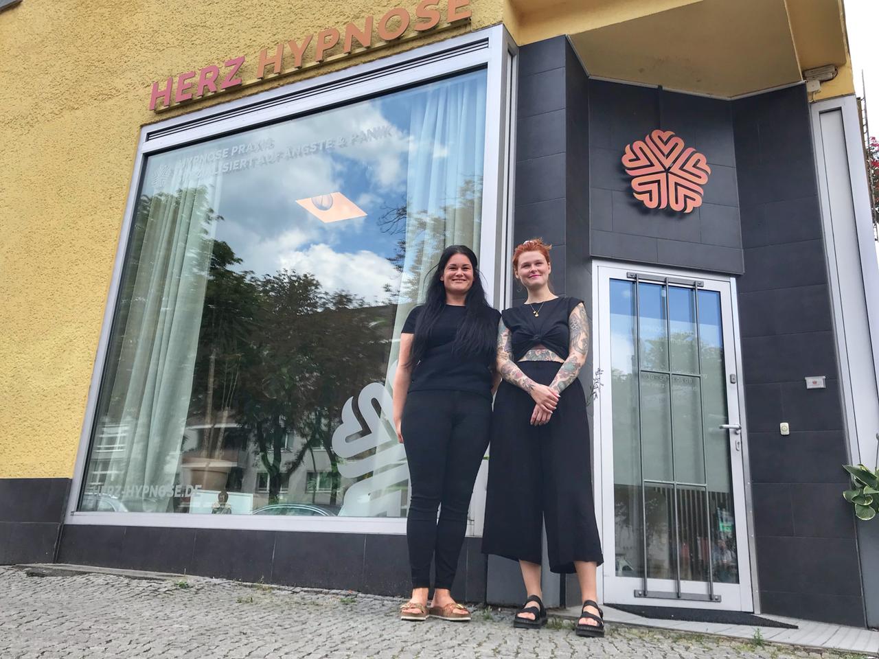 Sarah Peters und ihre Kollegin posieren vor einem Fenster, über dem der Schriftzug "Herz Hypnose" steht. Sarah Peters und ihre Kollegin posieren vor einem Fenster, über dem der Schriftzug "Herz Hypnose" steht.
