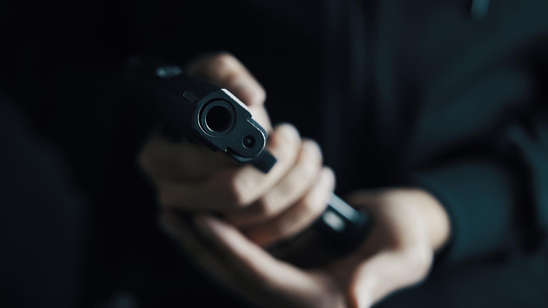 Eine Hand hält eine Pistole in die Kamera Eine Hand hält eine Pistole in die Kamera