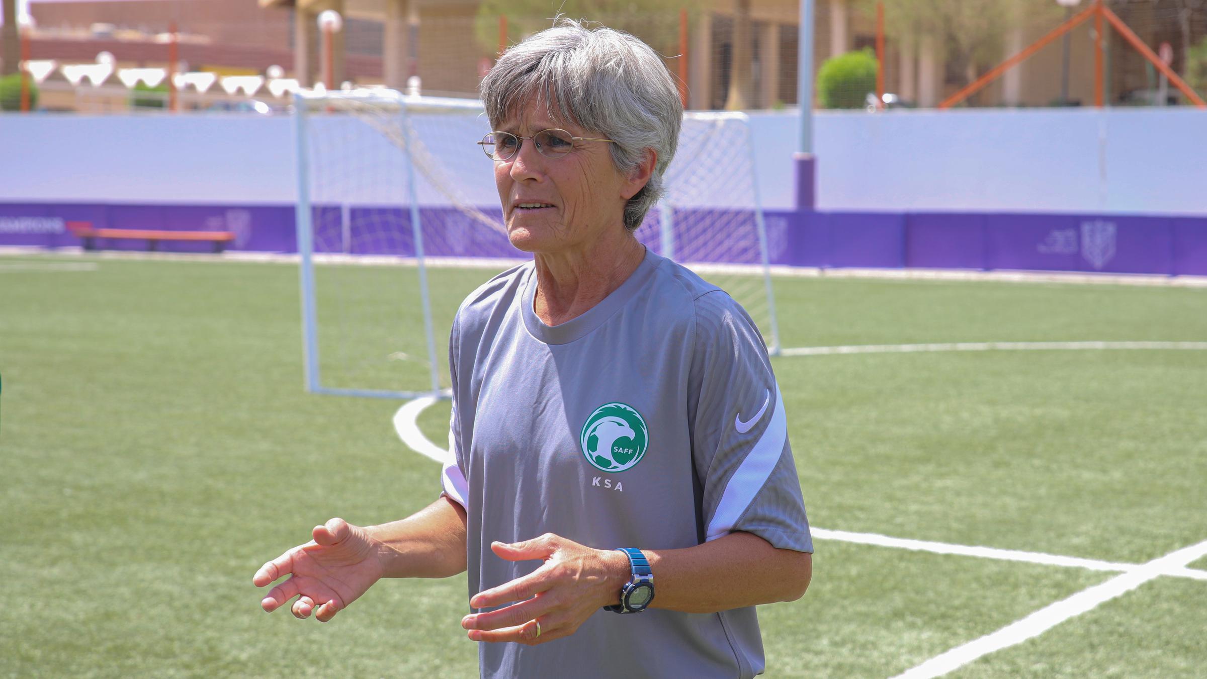 Eine Frau steht auf einem Trainingsplatz und gibt Anweisungen.