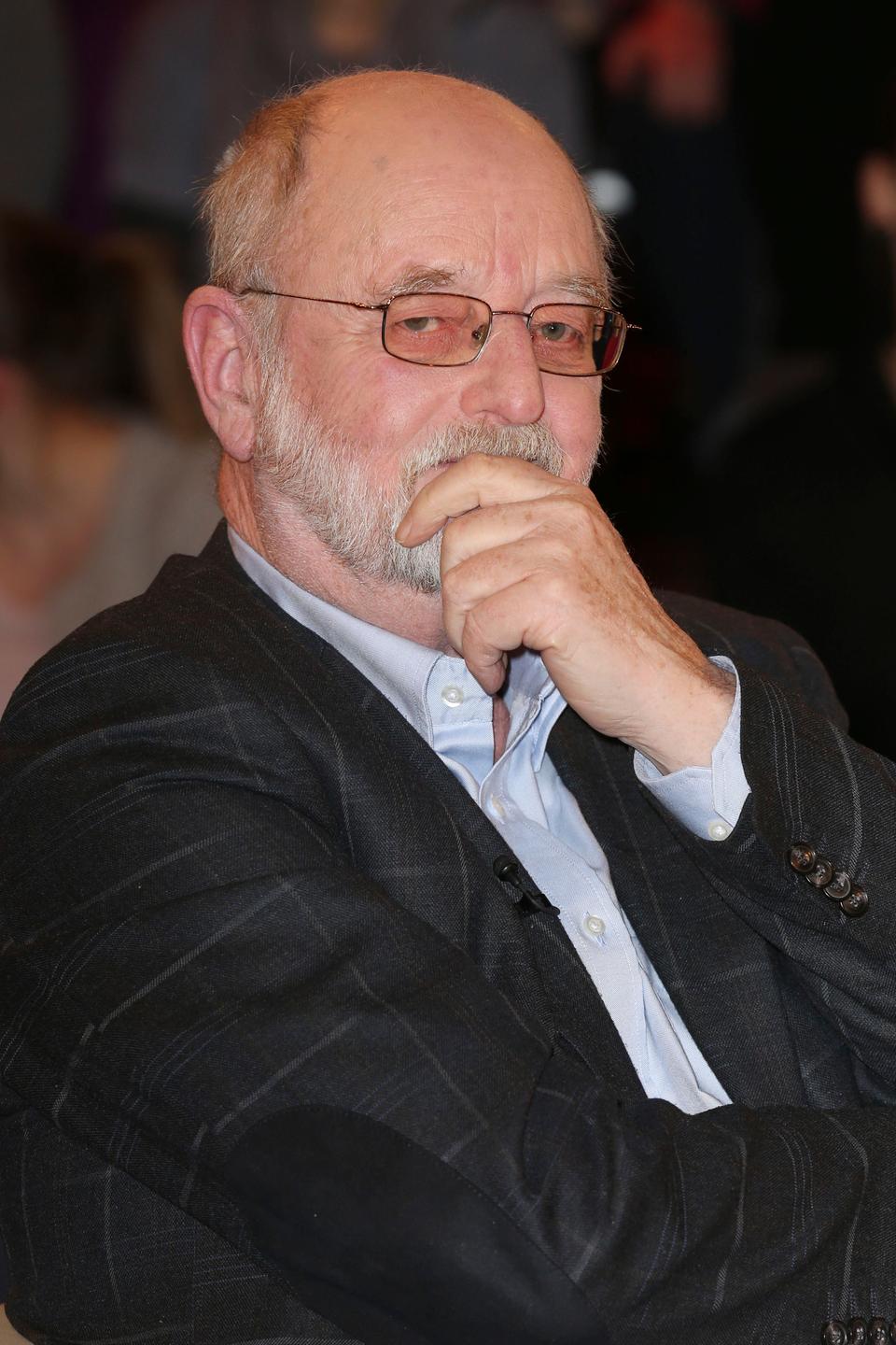 Porträt von Niklas Frank. Er trägt einen Bart und Brille und fasst sich mit der linken Hand nachdenklich ans Kinn. Porträt von Niklas Frank. Er trägt einen Bart und Brille und fasst sich mit der linken Hand nachdenklich ans Kinn.