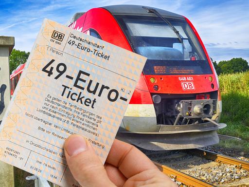 Fotomontage: Eine Hand hält ein 49-Euro-Ticket vor einer Regionalbahn (Symbolfoto)
