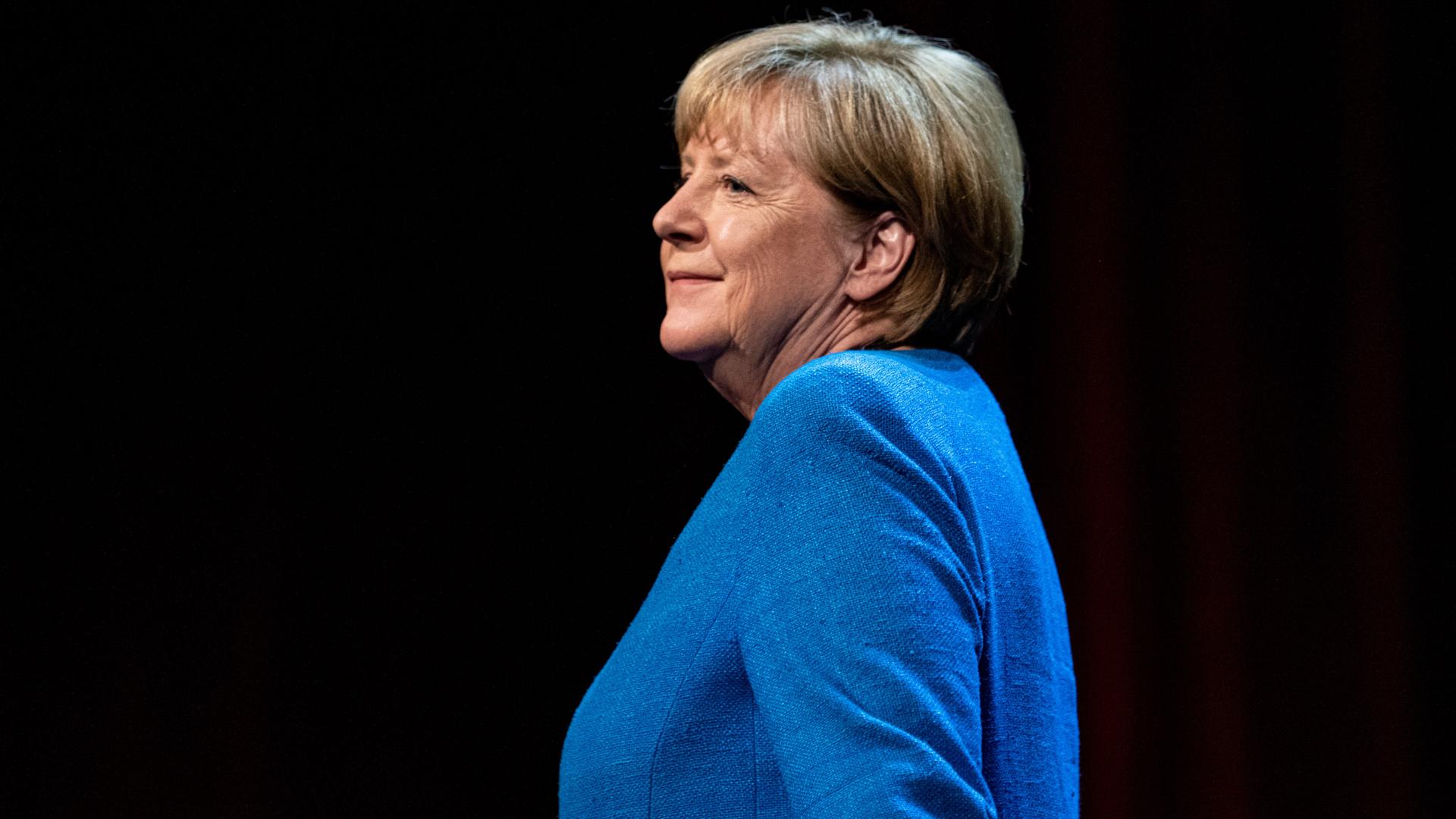 Altkanzlerin Merkel lächet still bei ihrem Gang auf der Bühne zum Gespräch im Berliner Ensemble.