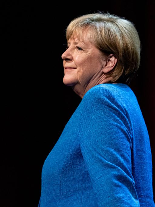 Altkanzlerin Merkel lächet still bei ihrem Gang auf der Bühne zum Gespräch im Berliner Ensemble.