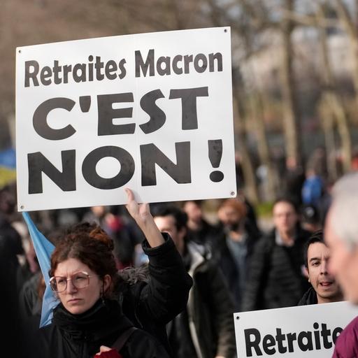 Eine Frau hält ein Protestplakat in die Luft. Ringsherum sieht man andere Protest-Teilnehmer.