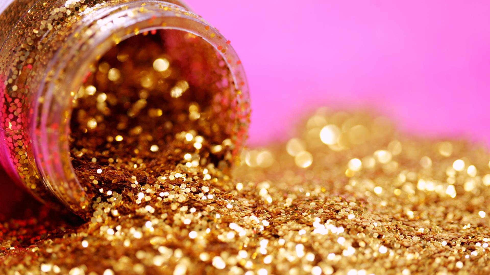 Goldener Glitzer läuft aus einem kleinen Glasbehälter. Goldener Glitzer läuft aus einem kleinen Glasbehälter.