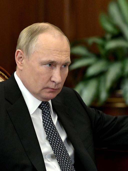 Russlands Staatspräsident Wladimir Putin sitzt an einem Schreibtisch mit einem Stift in der Hand.