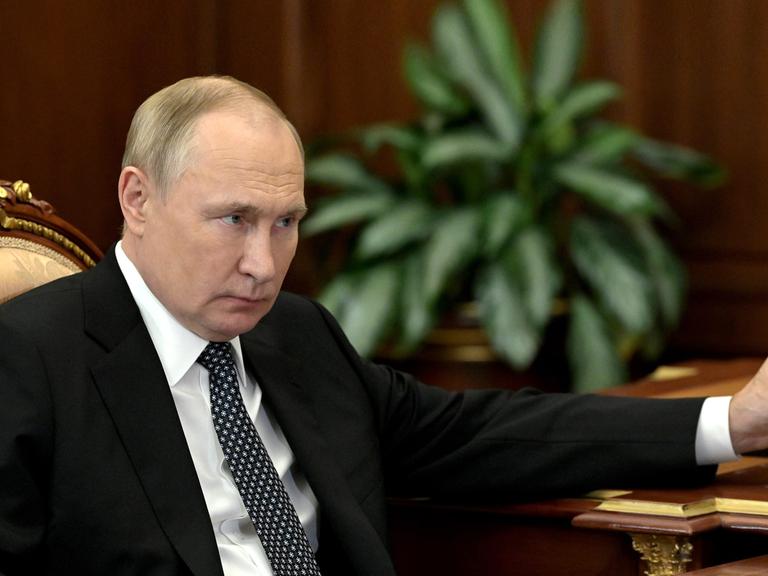 Russlands Staatspräsident Wladimir Putin sitzt an einem Schreibtisch mit einem Stift in der Hand.