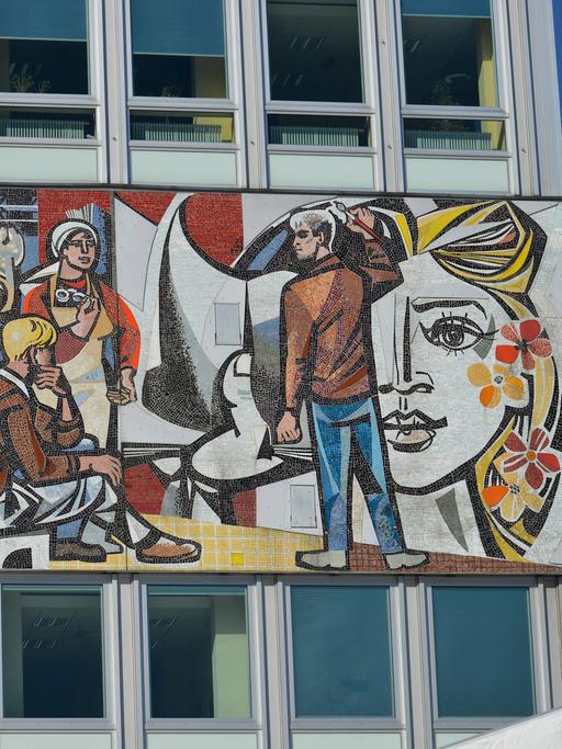 Auf einem Wandgemälde sind Werktätige der DDR abgebildet. 