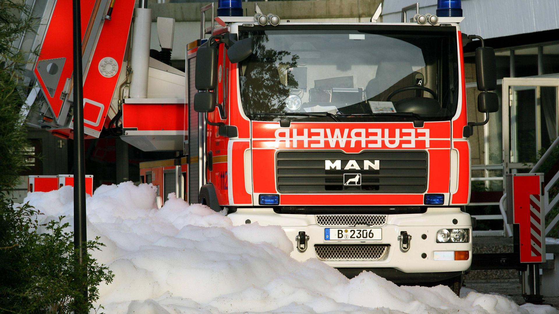 Ein Feuerwehrauto der Berliner Feuerwehr. Davor Löschschaum auf dem Boden. Ein Feuerwehrauto der Berliner Feuerwehr. Davor Löschschaum auf dem Boden.