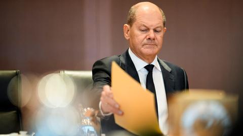 Bundeskanzler Scholz sitzt an einem Tisch beim Kabinettstreffen in Berlin und sortiert einige Akten.