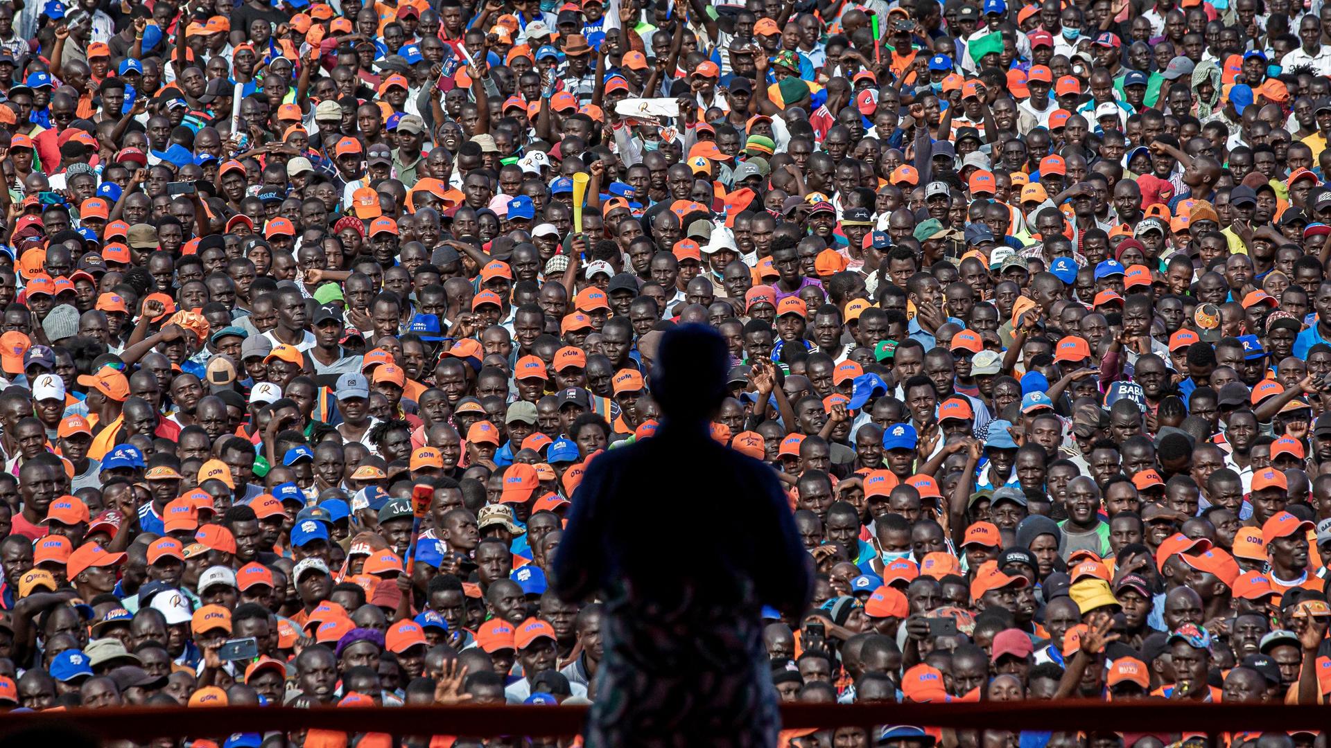 Silhouette eines Mannes, der vor einer großen Menschenmenge eine Rede hält. Silhouette eines Mannes, der vor einer großen Menschenmenge eine Rede hält.