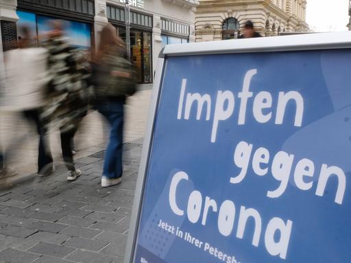 Ein Aufsteller mit dem Schriftzug "Impfen gegen Corona" steht vor einer Apotheke.