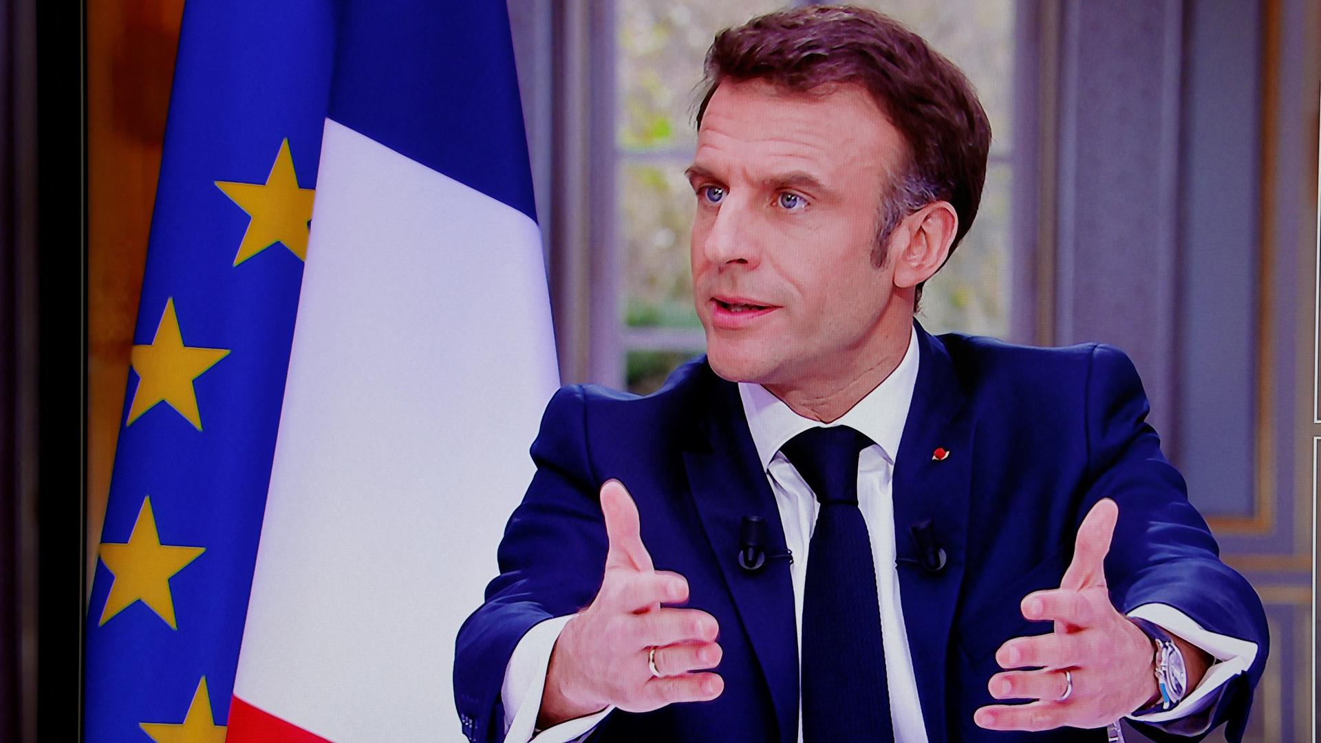 Frankreich, Paris: Präsident Emmanuel Macron spricht bei einem Fernsehen-Interview im Elysee Palast. Er hält beide Arme vor sich und gestikuliert.