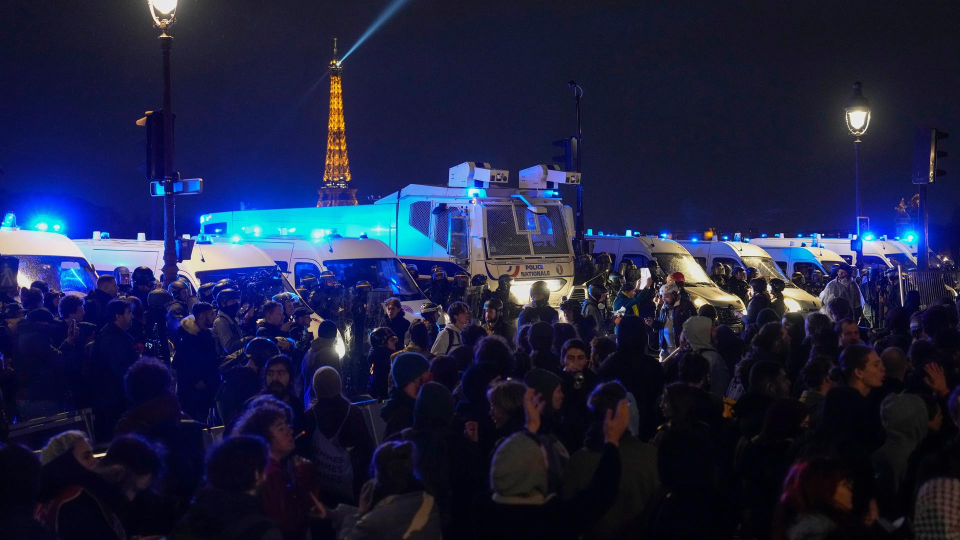 Ein Wasserwerfer der Polizei steht zwischen zahlreichen Demonstranten in Paris.