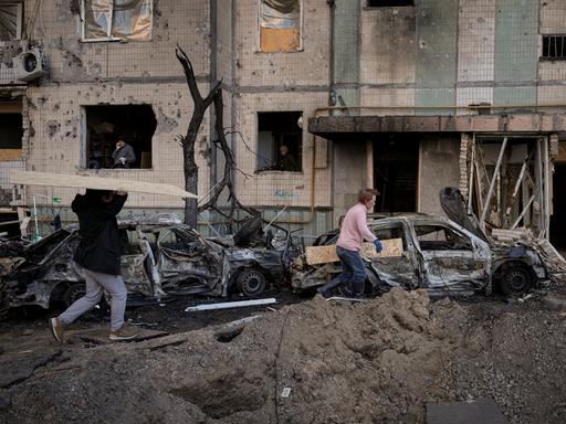 Menschen in Kiew tragen Holzbretter, um die Fenster eines Gebäudes abzudecken, das am Vortag bei einem Bombenangriff beschädigt wurde.