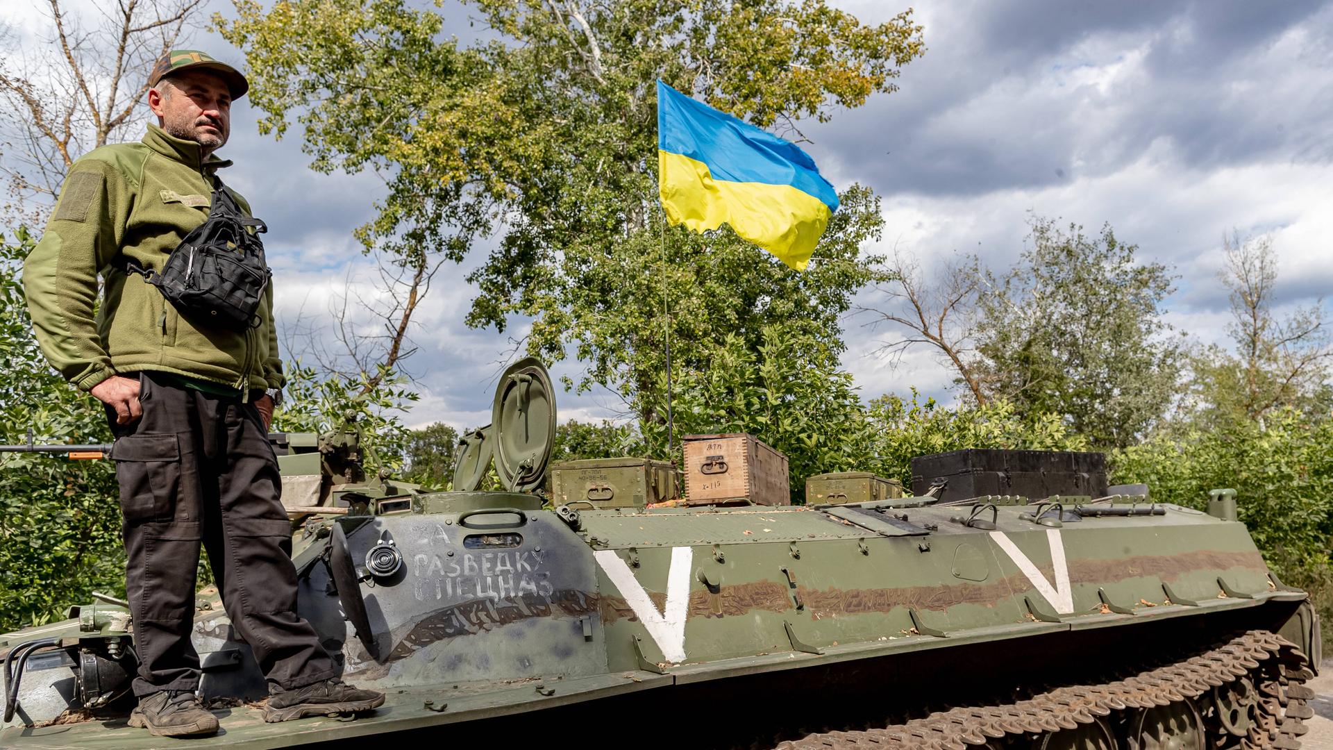 Ein ukrainischer Soldat und eine ukrainische Nationalflagge stehen auf einem verlassenen russischen Panzer, der von den ukrainischen Streitkräften in der Ostukraine am 8. September 2022 erbeutet wurde Ein ukrainischer Soldat und eine ukrainische Nationalflagge stehen auf einem verlassenen russischen Panzer, der von den ukrainischen Streitkräften in der Ostukraine am 8. September 2022 erbeutet wurde